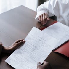 Adults reviewing legal documents on a wooden desk indoors, highlighting professional collaboration.