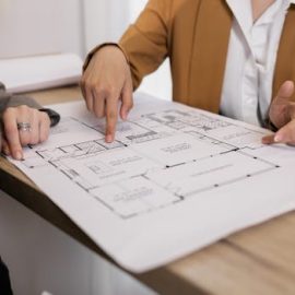 Two professionals reviewing architectural plans, focused on floor layout and design details.